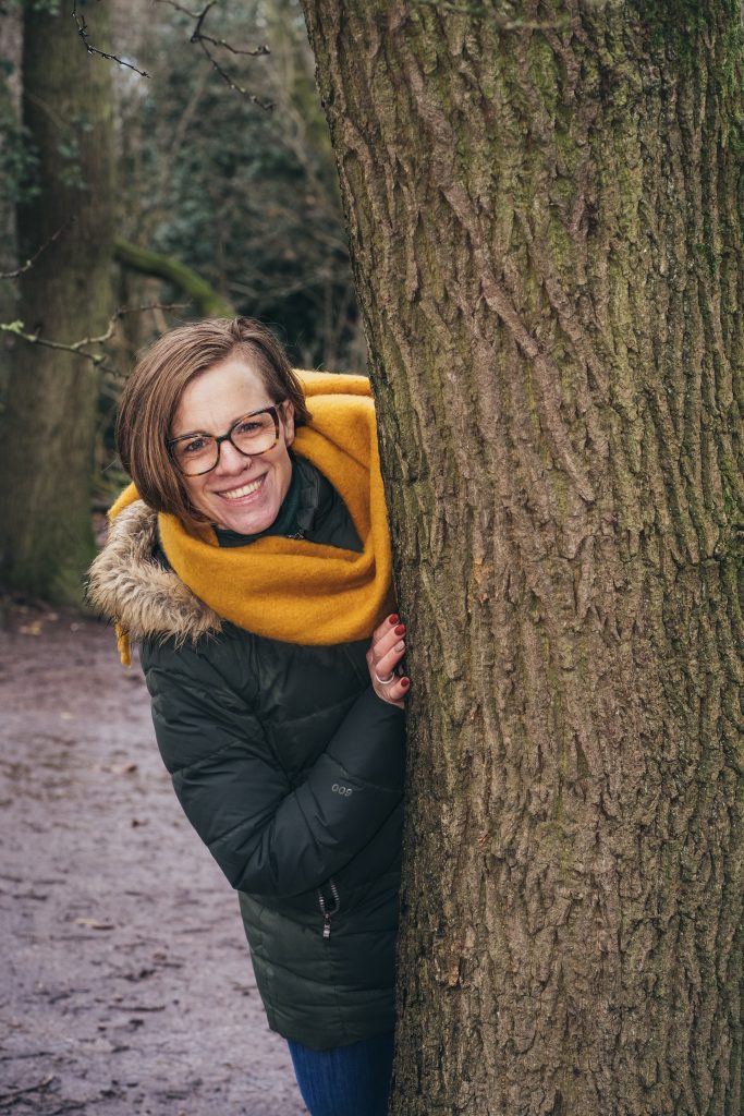 A woman hiding behind a tree