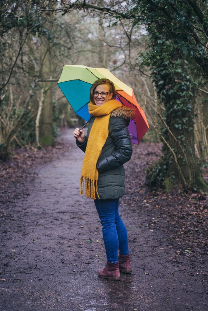 Woman standing in the forest with colourful umbrella